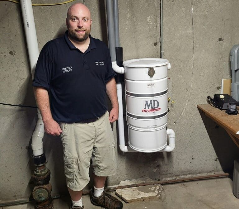 Man stands next to a central vacuum system in a basement.