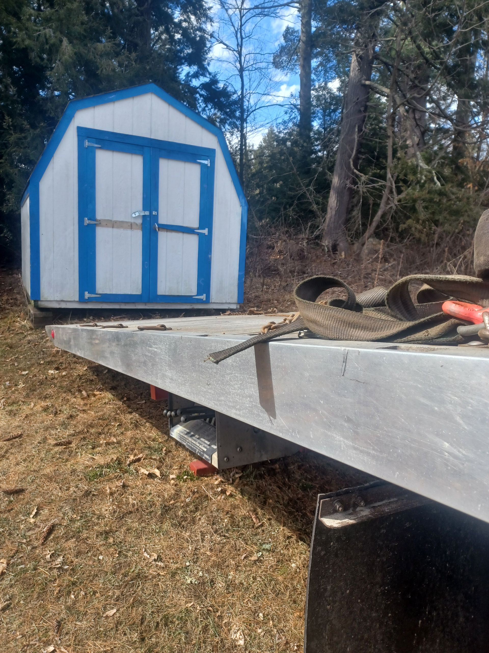 A Blue and White Barn Shed Is Sitting on Top of A Tow Truck.