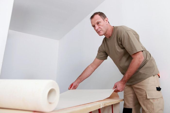 man laying out wallpaper in Orange County
