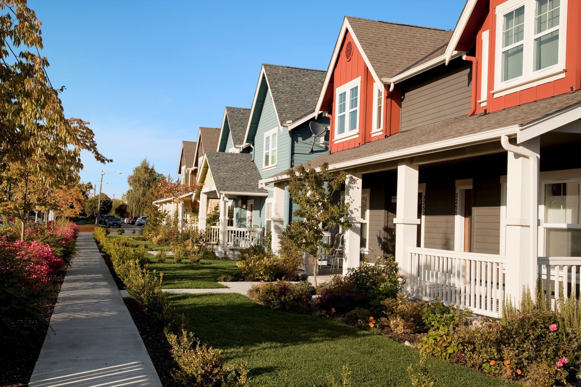 Row of colorful houses with porches along a sidewalk.