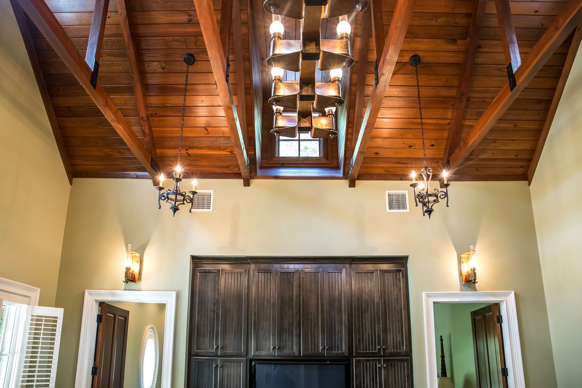 Vaulted ceiling with wood beams, chandeliers, and cream walls.