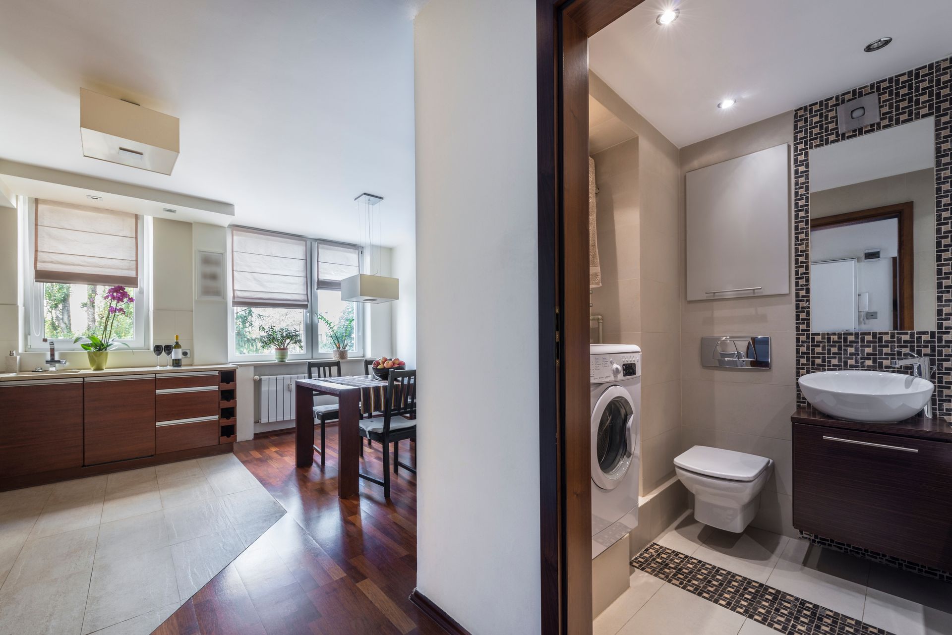 A combined kitchen and dining area opens to a bathroom with a toilet, washing machine, and sink.