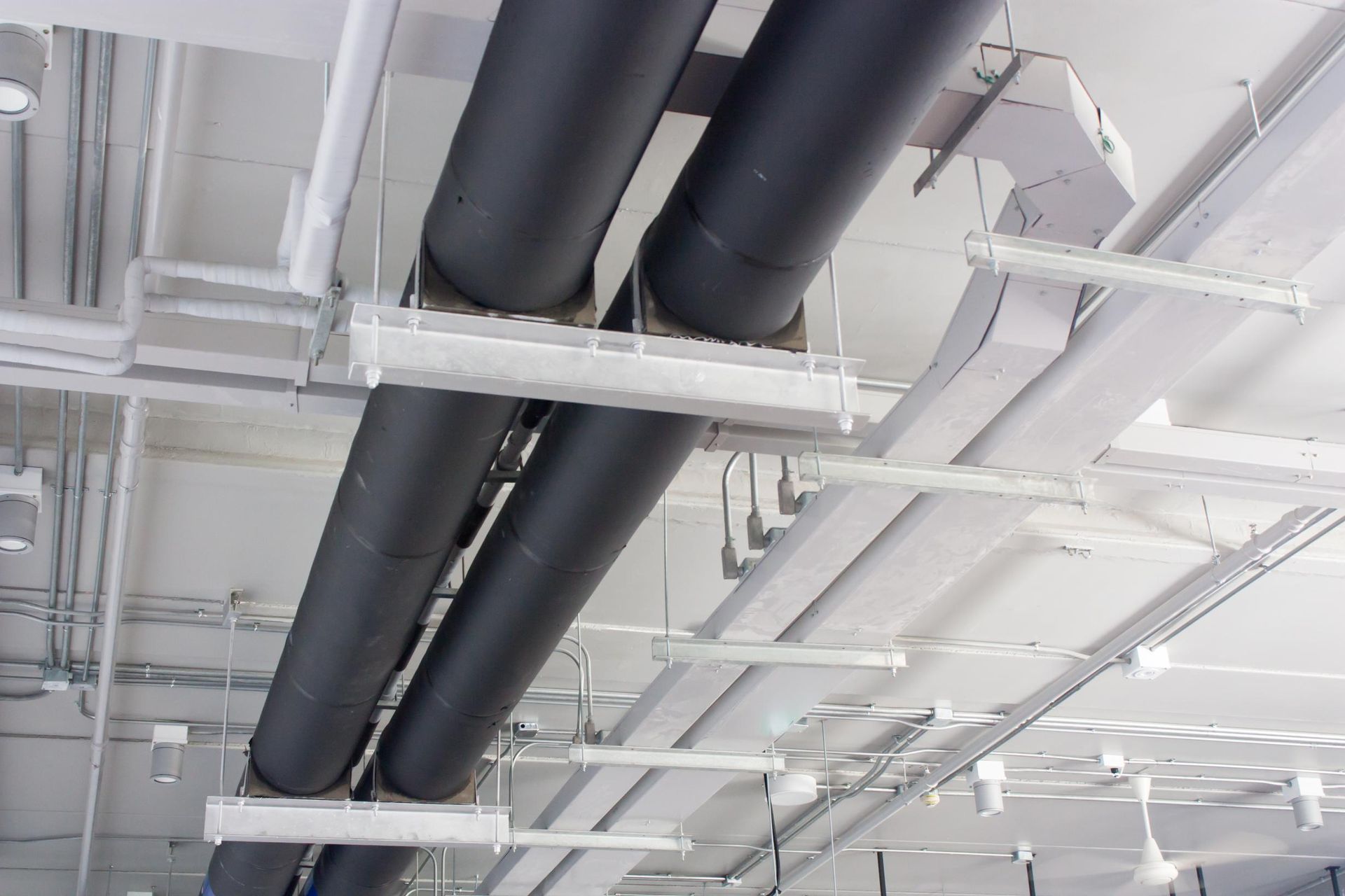 A bunch of pipes are hanging from the ceiling of a building.