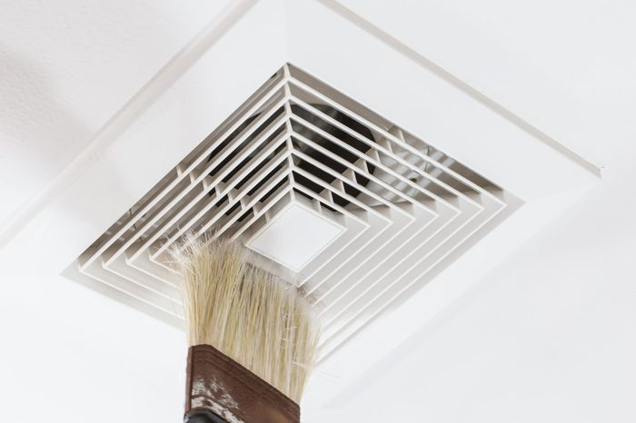 A brush is being used to clean a vent on the ceiling.