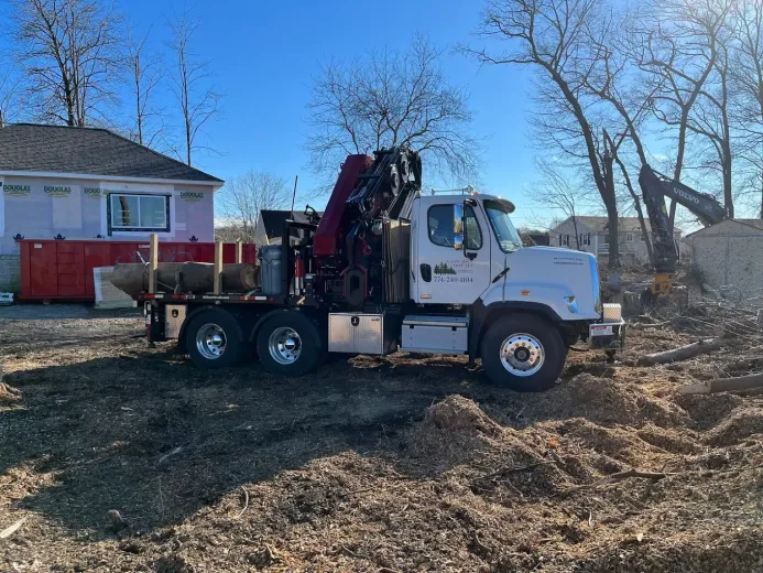 A white truck is parked in a dirt field in front of a house.