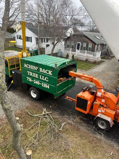 A tree chipper is being pulled by a green truck.
