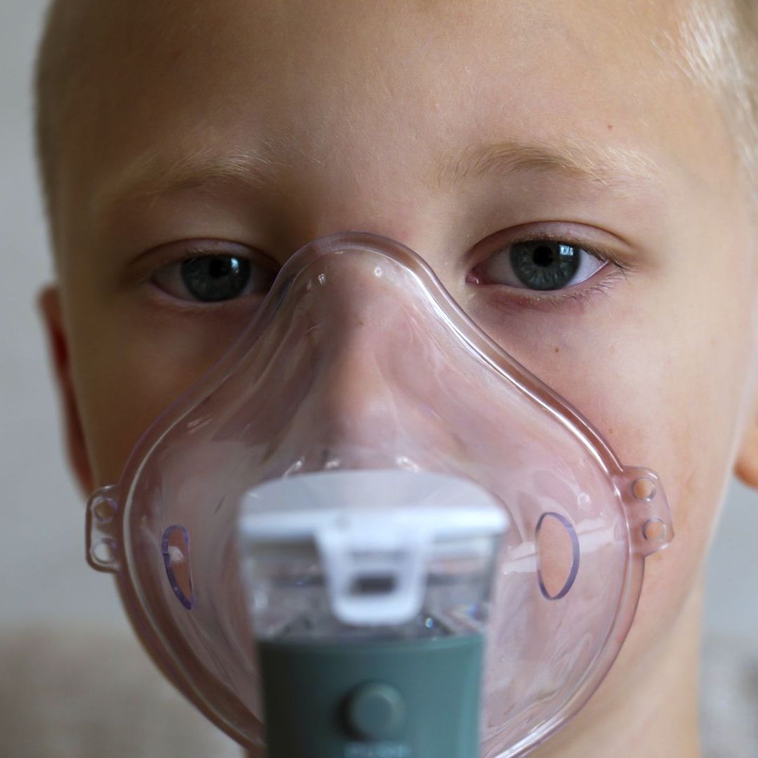 A young boy is wearing an oxygen mask on his face.