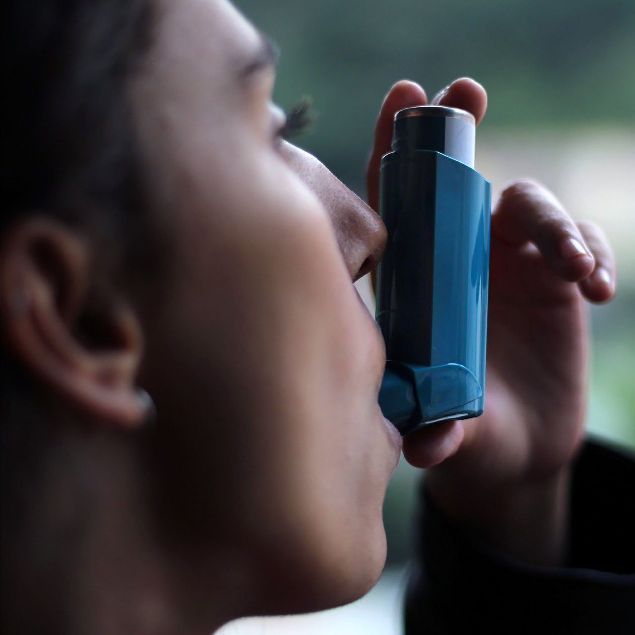 A close up of a person using an inhaler