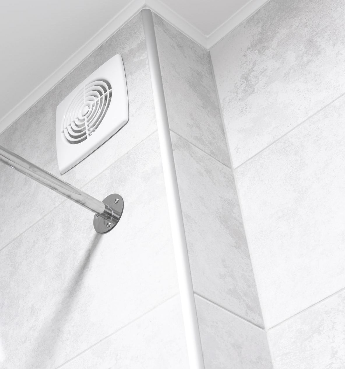 A bathroom with a shower head and a fan on the wall