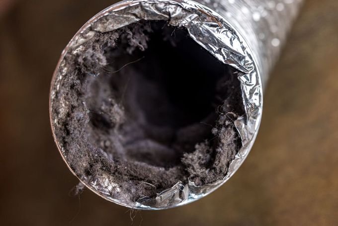 A close up of a dirty duct with dust coming out of it.