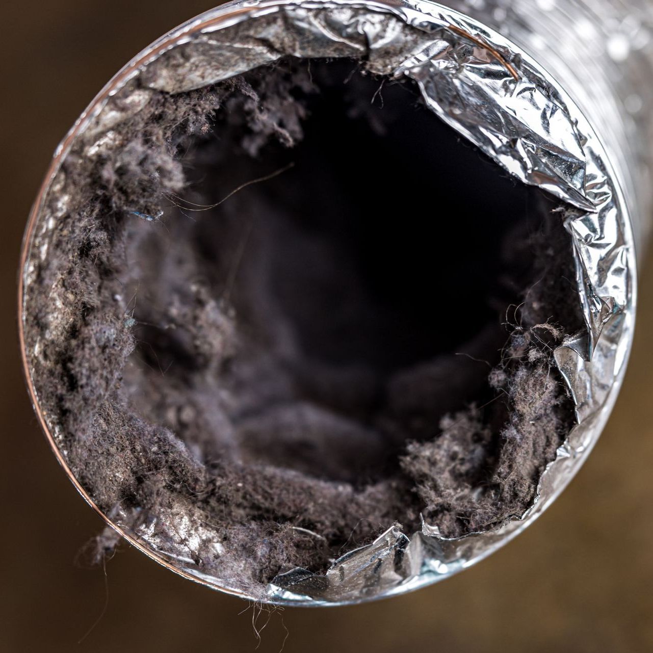 A close up of a dirty duct with a lot of dust coming out of it.