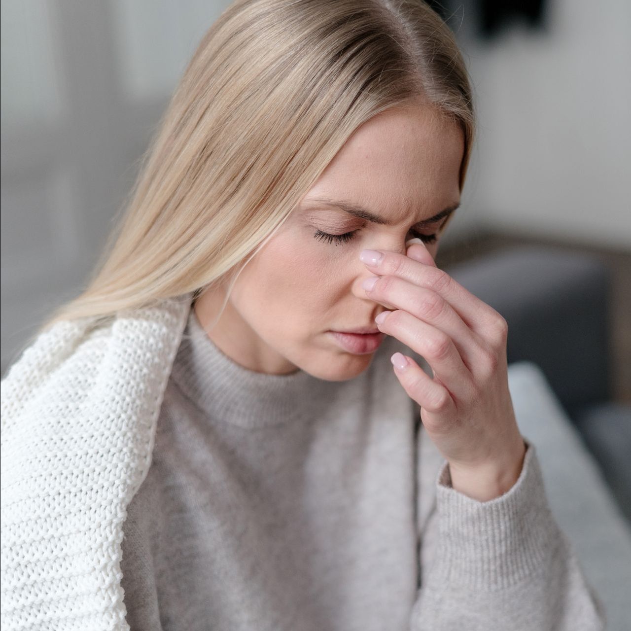 A woman is holding her nose because she has a headache.