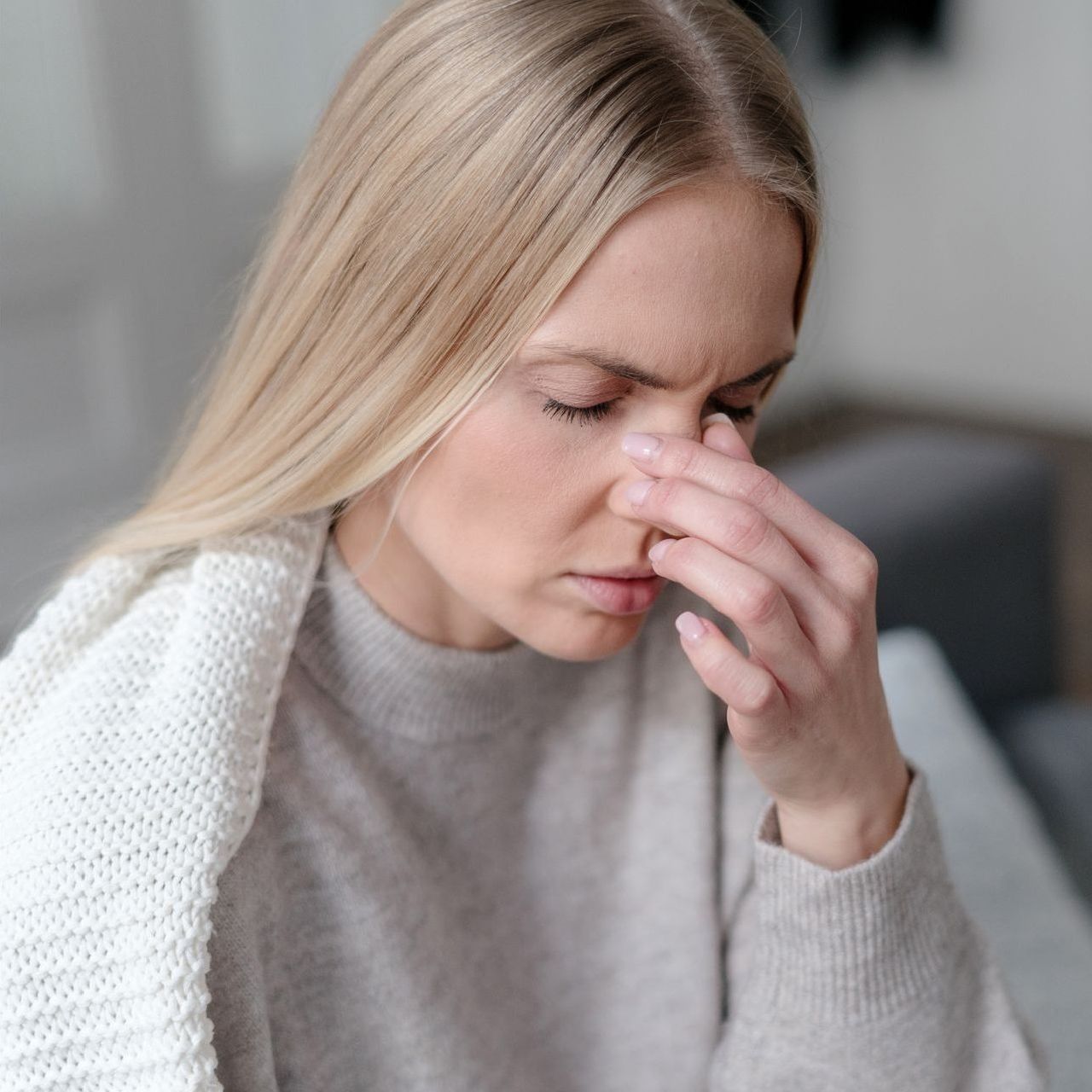 A woman is holding her nose because she has a headache.