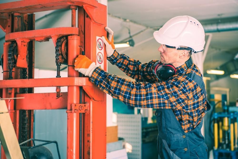 Man is Working on a Forklift in a Factory — Bundaberg Forklift Repairs Mundubbera, QLD