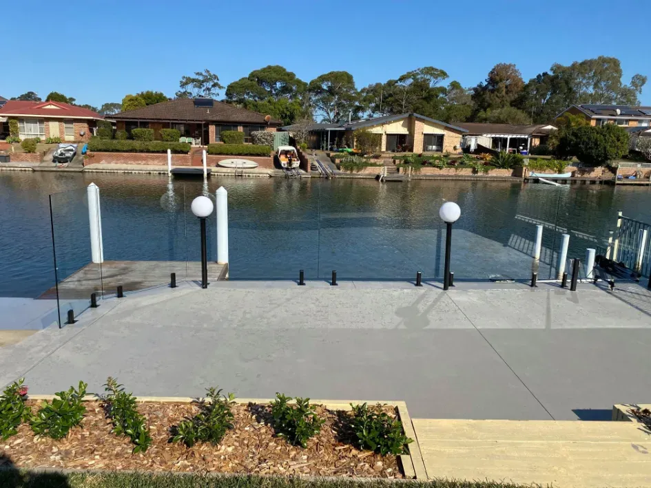 A dock with a glass railing overlooking a body of water — Mid Coast Glass Fencing In Bonny Hills, NSW