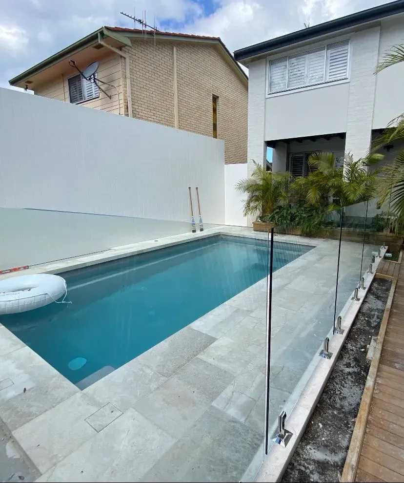 A large swimming pool is surrounded by a glass fence — Mid Coast Glass Fencing In Hallidays Point, NSW