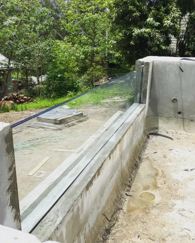 A swimming pool is being built with a glass fence around it — Mid Coast Glass Fencing In Laurieton, NSW