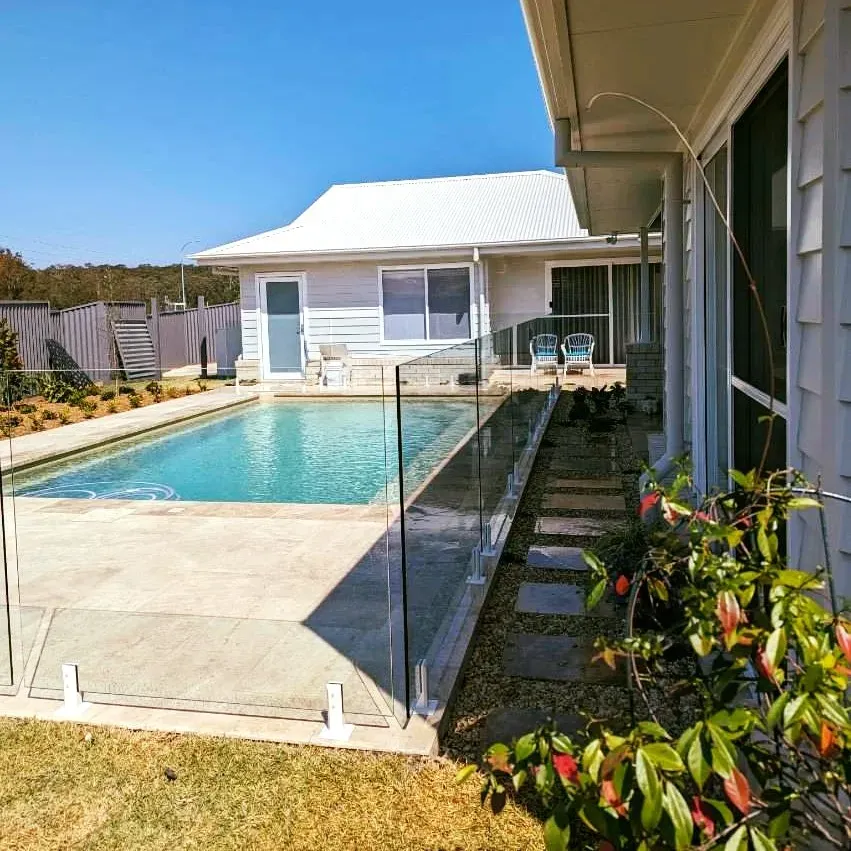A house with a large swimming pool in front of it — Mid Coast Glass Fencing In Laurieton, NSW