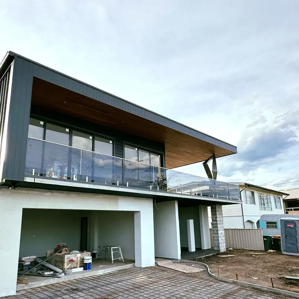 A large house with a balcony and a lot of windows is being built — Mid Coast Glass Fencing In Hallidays Point, NSW