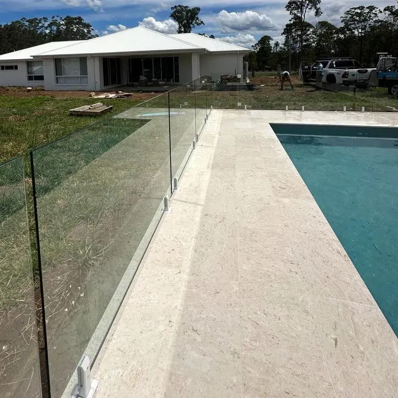 A swimming pool with a glass fence and a house in the background — Mid Coast Glass Fencing In Hallidays Point, NSW