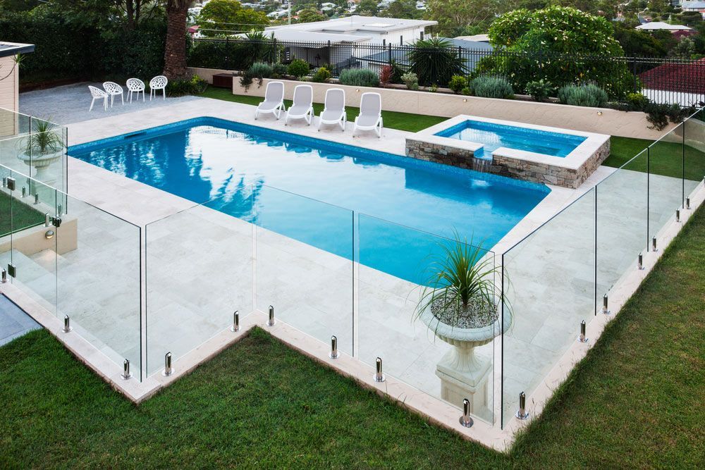 A large swimming pool with a glass fence around it — Mid Coast Glass Fencing In Port Macquarie, NSW