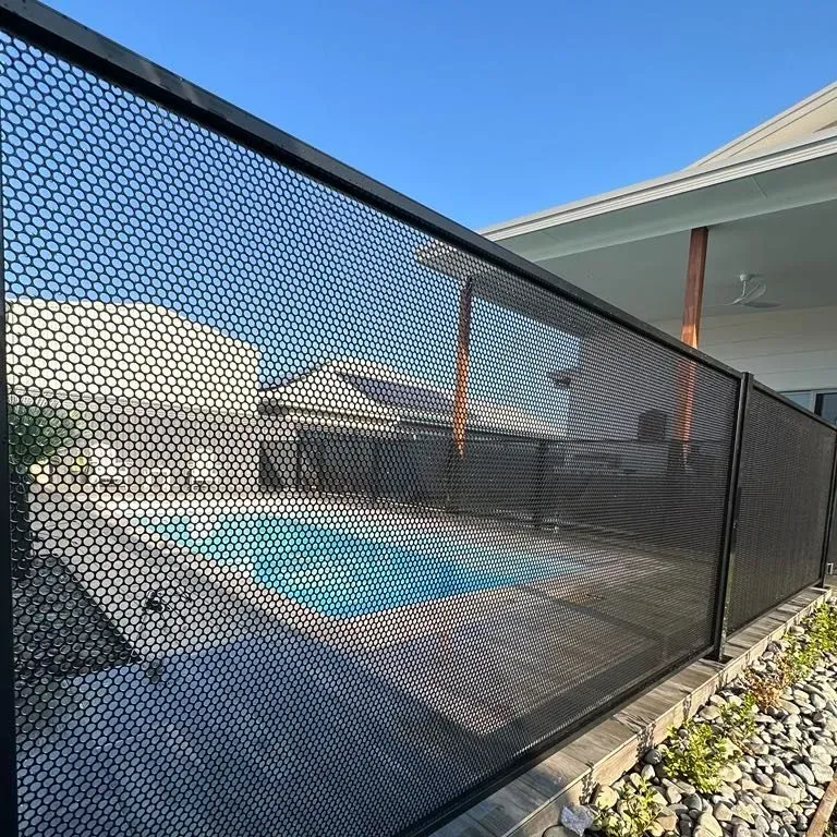 A Black Fence Surrounds A Swimming Pool In A BackyARD — Mid Coast Glass Fencing In Laurieton, NSW