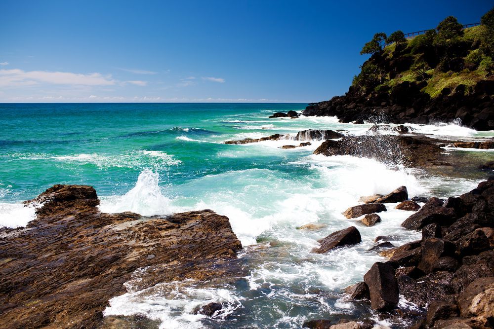 Waves crashing against a rocky shoreline on a sunny day — Mid Coast Glass Fencing In Hallidays Point, NSW