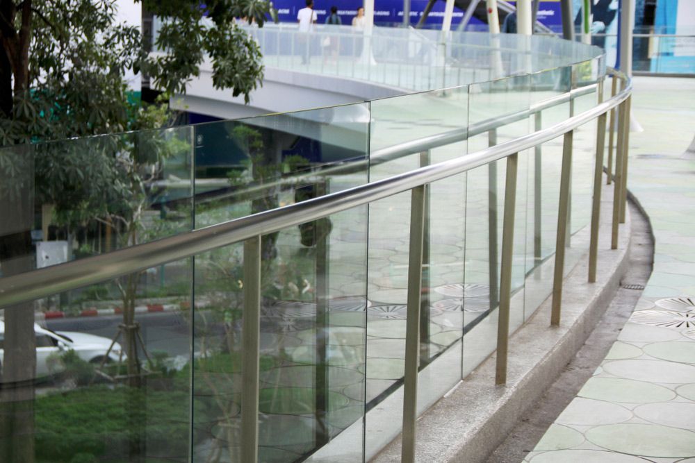 A glass railing with a stainless steel railing on a sidewalk — Mid Coast Glass Fencing In Forster, NSW