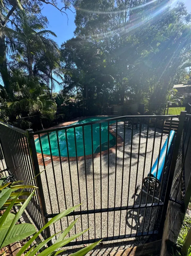 A Fence Surrounds A Swimming Pool In A BackyARD — Mid Coast Glass Fencing In Hallidays Point, NSW