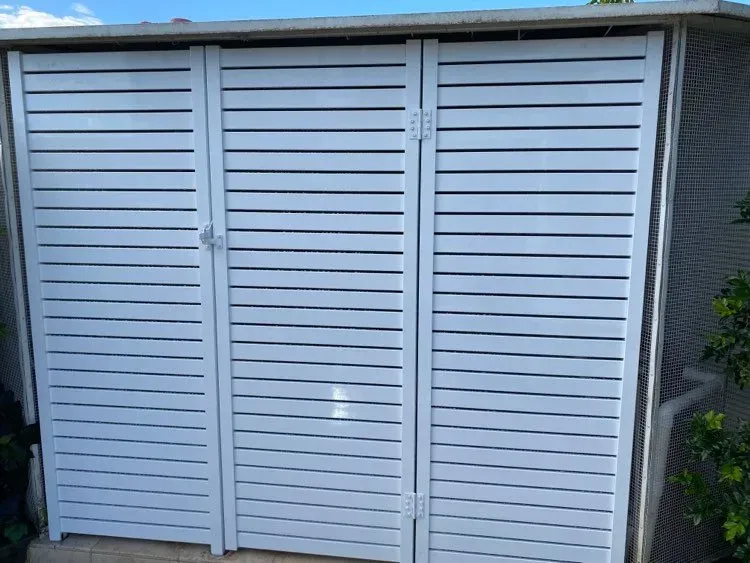 A White Fence With Three Doors Is Sitting Next To A Brick WALL — Mid Coast Glass Fencing In Forster, NSW
