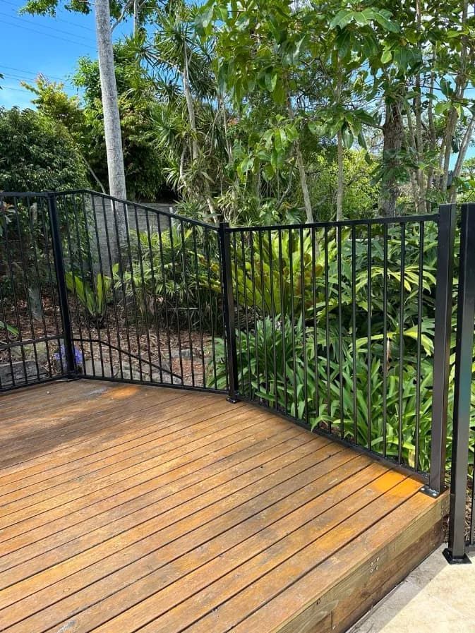 A Wooden Deck With A Metal Fence Around IT — Mid Coast Glass Fencing In Port Macquarie, NSW