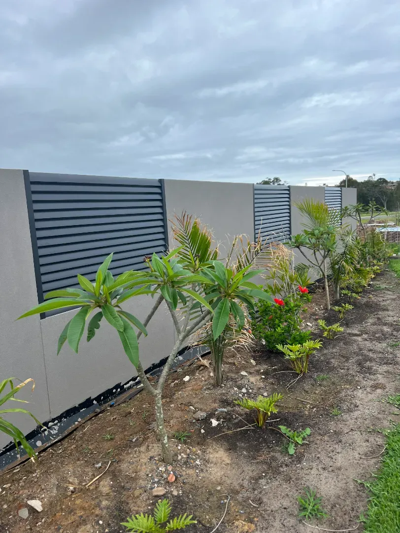 A fence with a row of plants in front of it — Mid Coast Glass Fencing In Forster, NSW