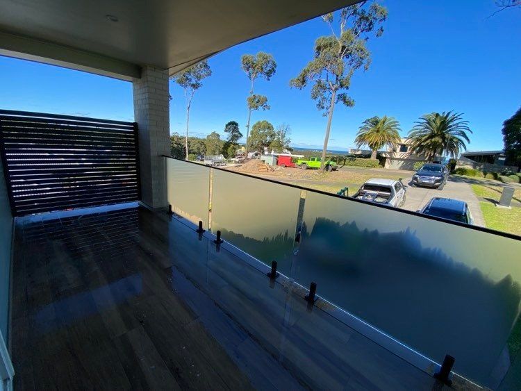 A balcony with a view of the ocean and palm trees — Mid Coast Glass Fencing In Old Bar, NSW