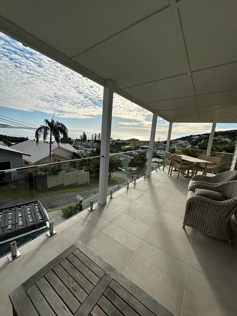 A Balcony With A View Of A City And A Table And ChaIRS — Mid Coast Glass Fencing In Taree, NSW