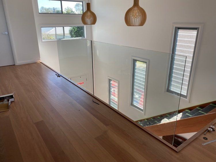 A Staircase With A Glass Railing And A Wooden Floor — Mid Coast Glass Fencing In Old Bar, NSW
