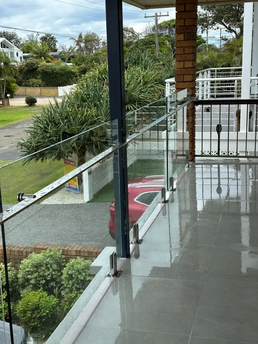 A Balcony With A Glass Railing And A Red Car Parked On IT — Mid Coast Glass Fencing In South West Rocks, NSW