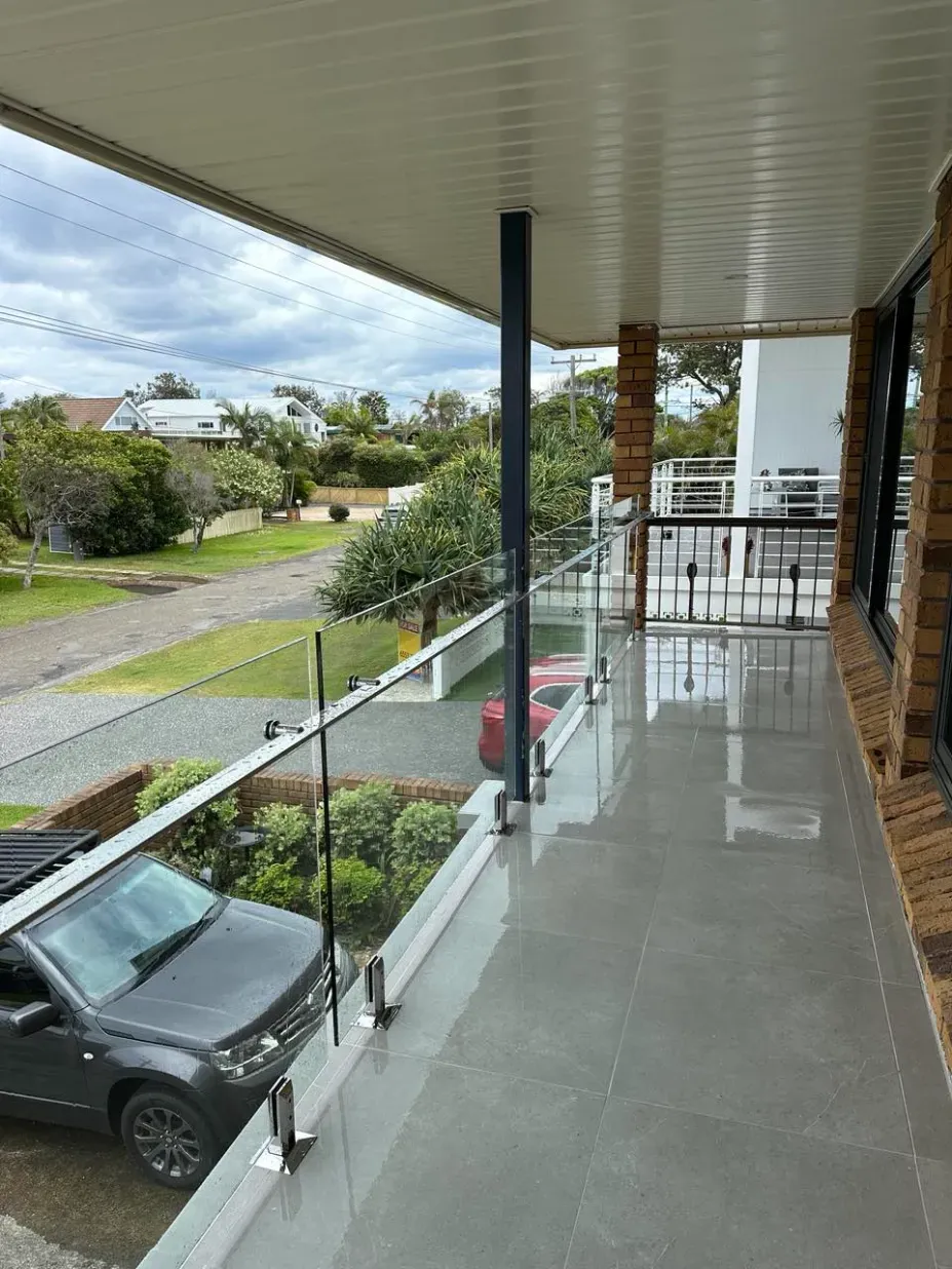 A balcony with a glass railing and a car parked on it — Mid Coast Glass Fencing In Taree, NSW