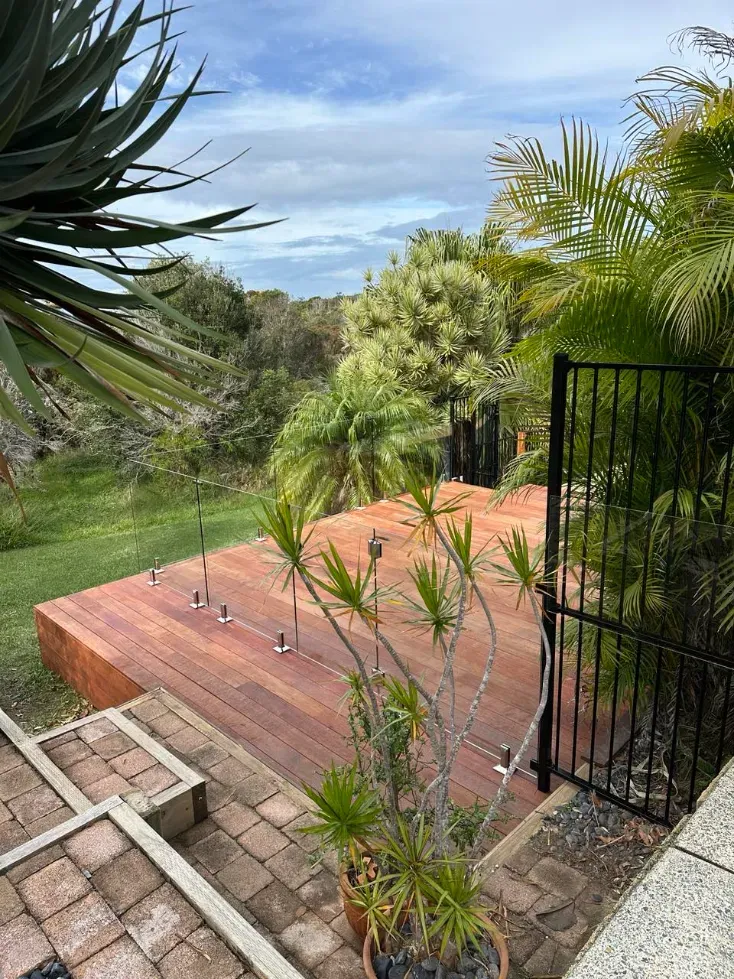 A wooden deck with stairs leading up to it and a fence surrounding it — Mid Coast Glass Fencing In Forster, NSW