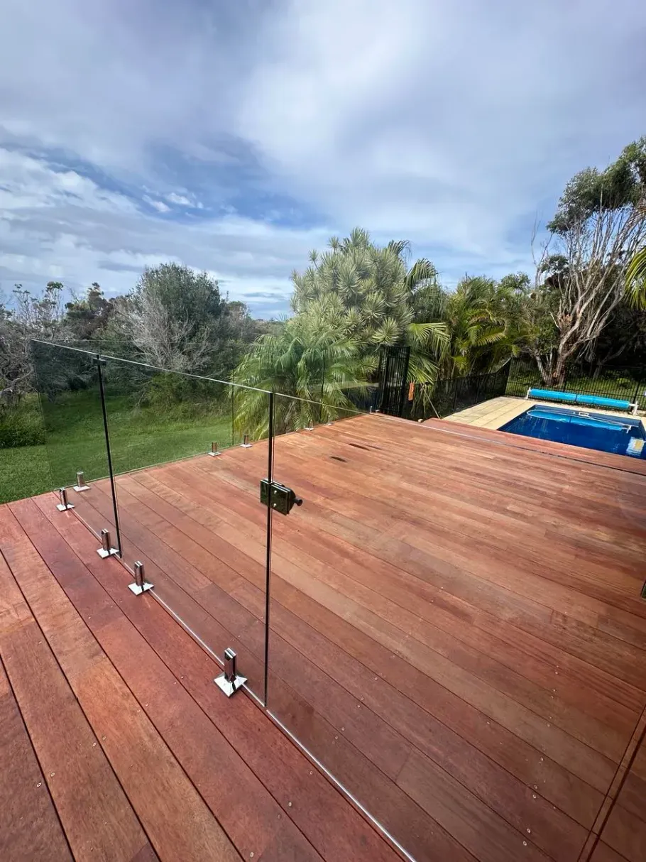 A Wooden Deck With A Glass Railing And A Swimming Pool In The BackgroUND — Mid Coast Glass Fencing In Forster, NSW