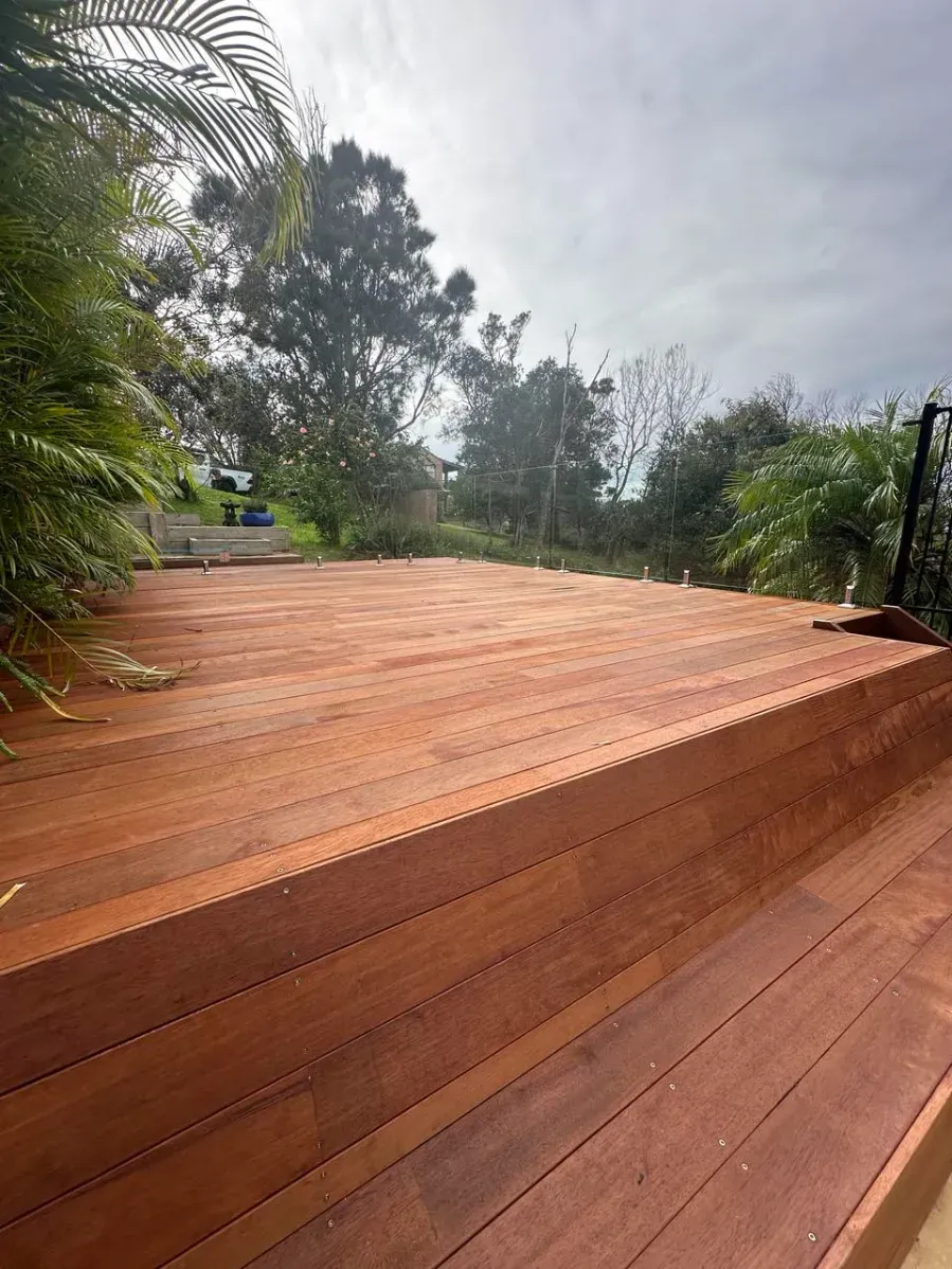 A wooden deck with stairs leading up to it and trees in the background — Mid Coast Glass Fencing In Forster, NSW