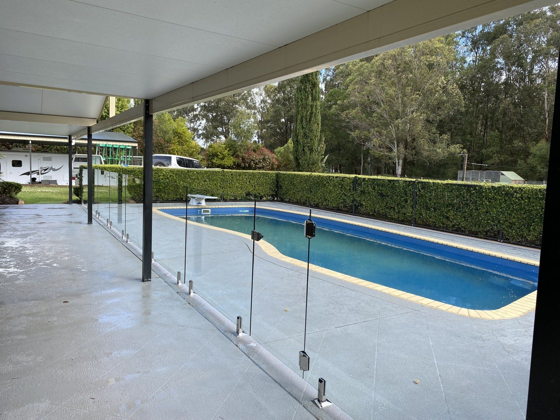 A Large Swimming Pool Is Surrounded By A Glass Fence — Mid Coast Glass Fencing In Old Bar, NSW