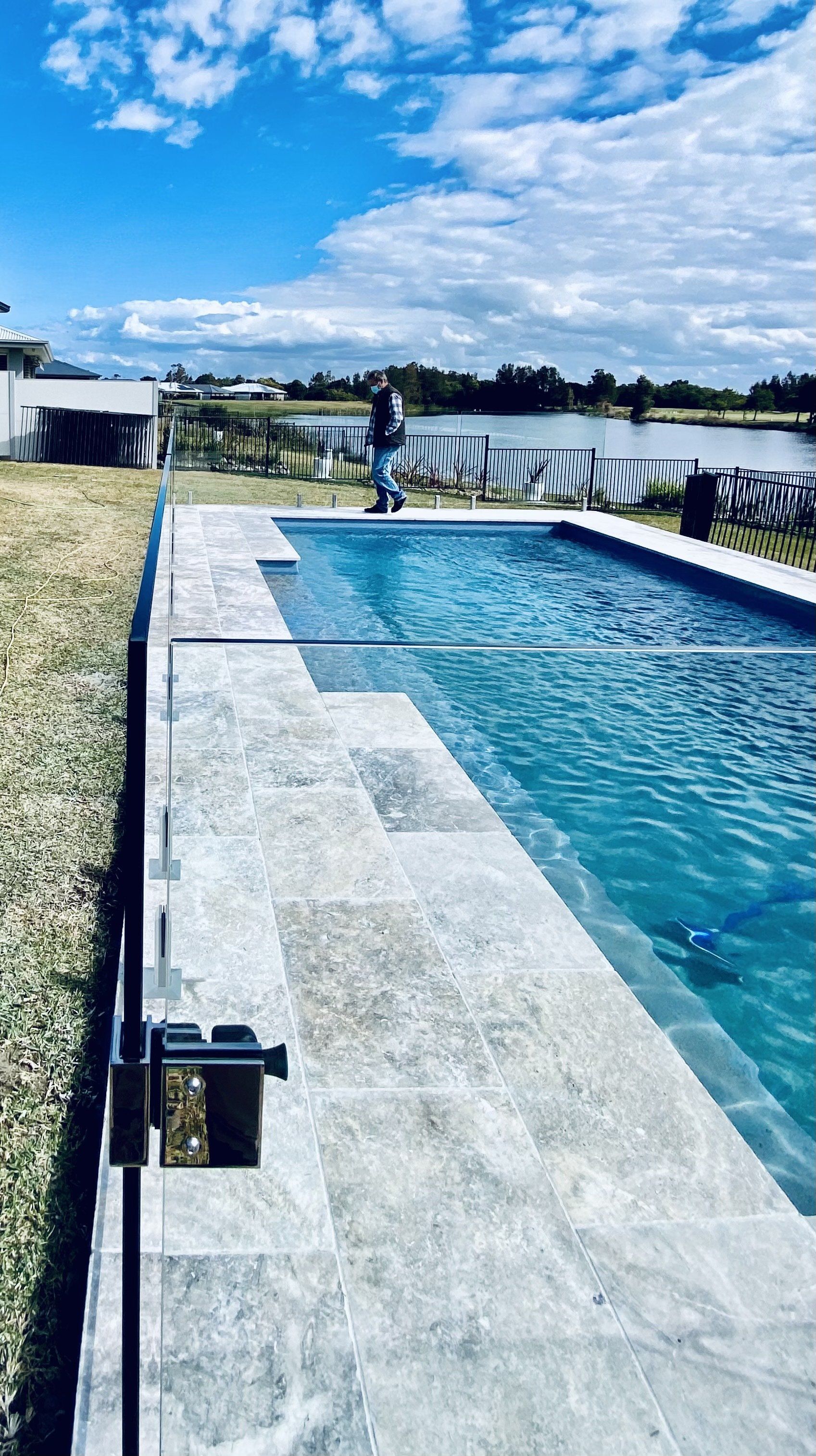 A Man Is Standing On The Edge Of A Swimming Pool — Mid Coast Glass Fencing In Old Bar, NSW