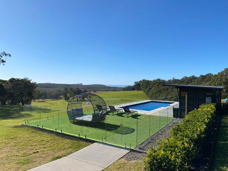 A Swimming Pool Is Surrounded By A Glass Fence In A Backyard — Mid Coast Glass Fencing In Old Bar, NSW