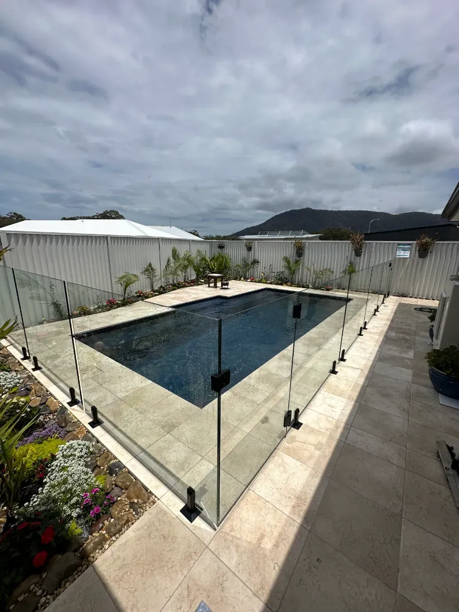 A Large Swimming Pool With A Glass Fence Around IT — Mid Coast Glass Fencing In Wauchope, NSW
