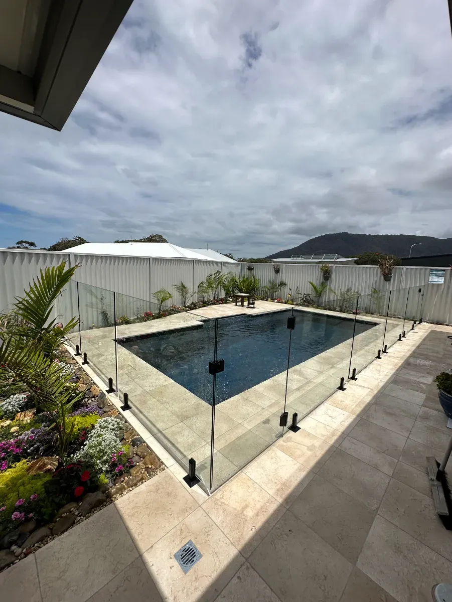 A Large Swimming Pool Surrounded By A Glass Fence In A BackyARD — Mid Coast Glass Fencing In Bonny Hills, NSW