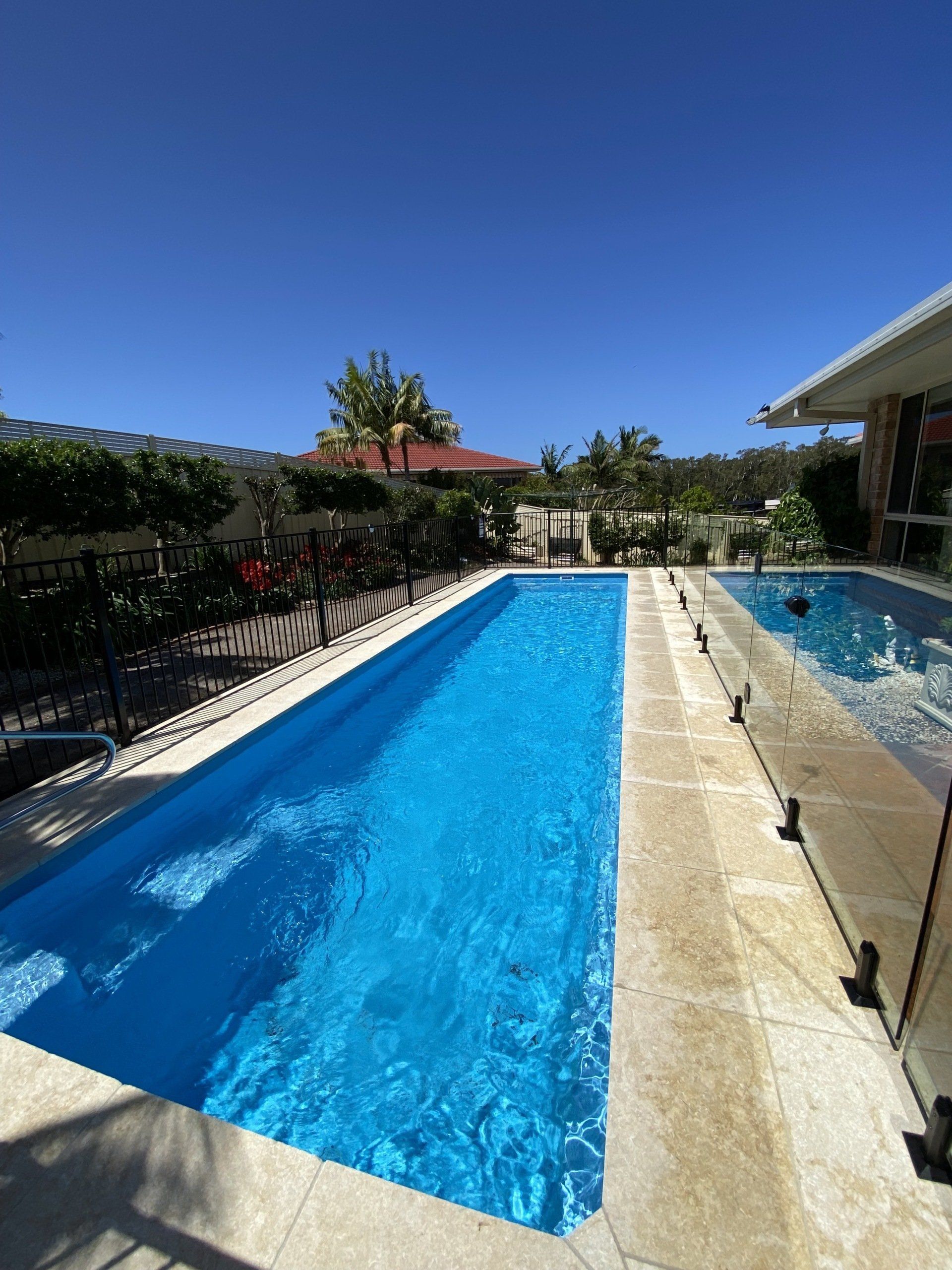 A large swimming pool in the backyard of a house — Mid Coast Glass Fencing In Old Bar, NSW
