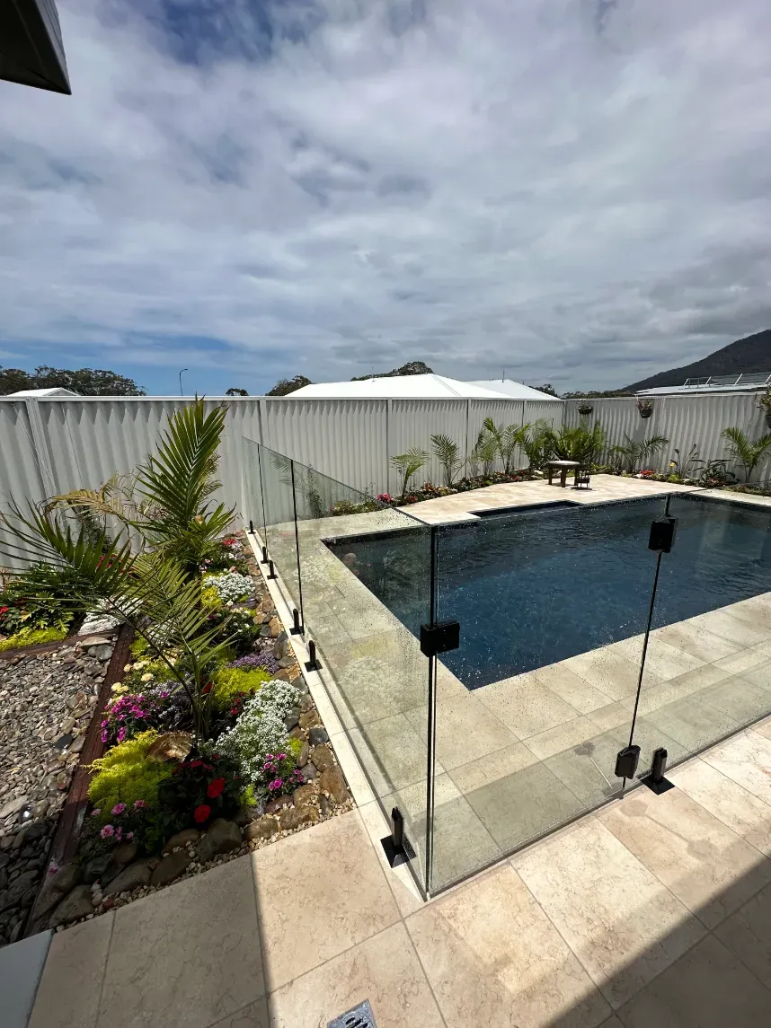 A Large Swimming Pool Is Surrounded By A Glass FeNCE — Mid Coast Glass Fencing In Laurieton, NSW