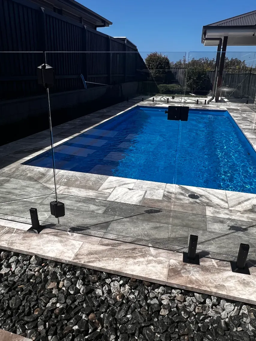 A Large Swimming Pool With A Glass Fence Around IT — Mid Coast Glass Fencing In Taree, NSW