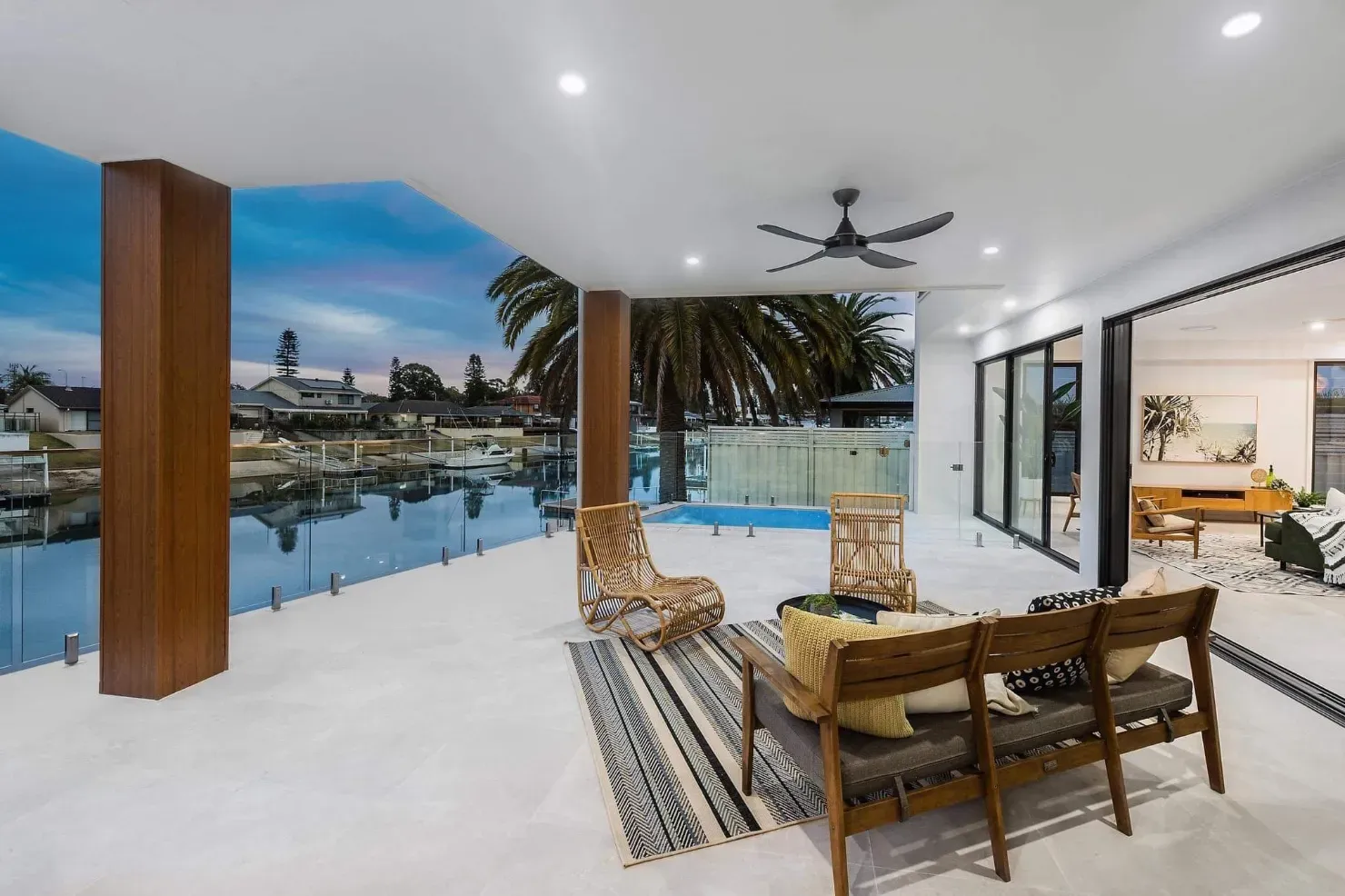 A Living Room With A Couch , Chairs And A Ceiling Fan Overlooking A Body Of WaTER — Mid Coast Glass Fencing In Hallidays Point, NSW