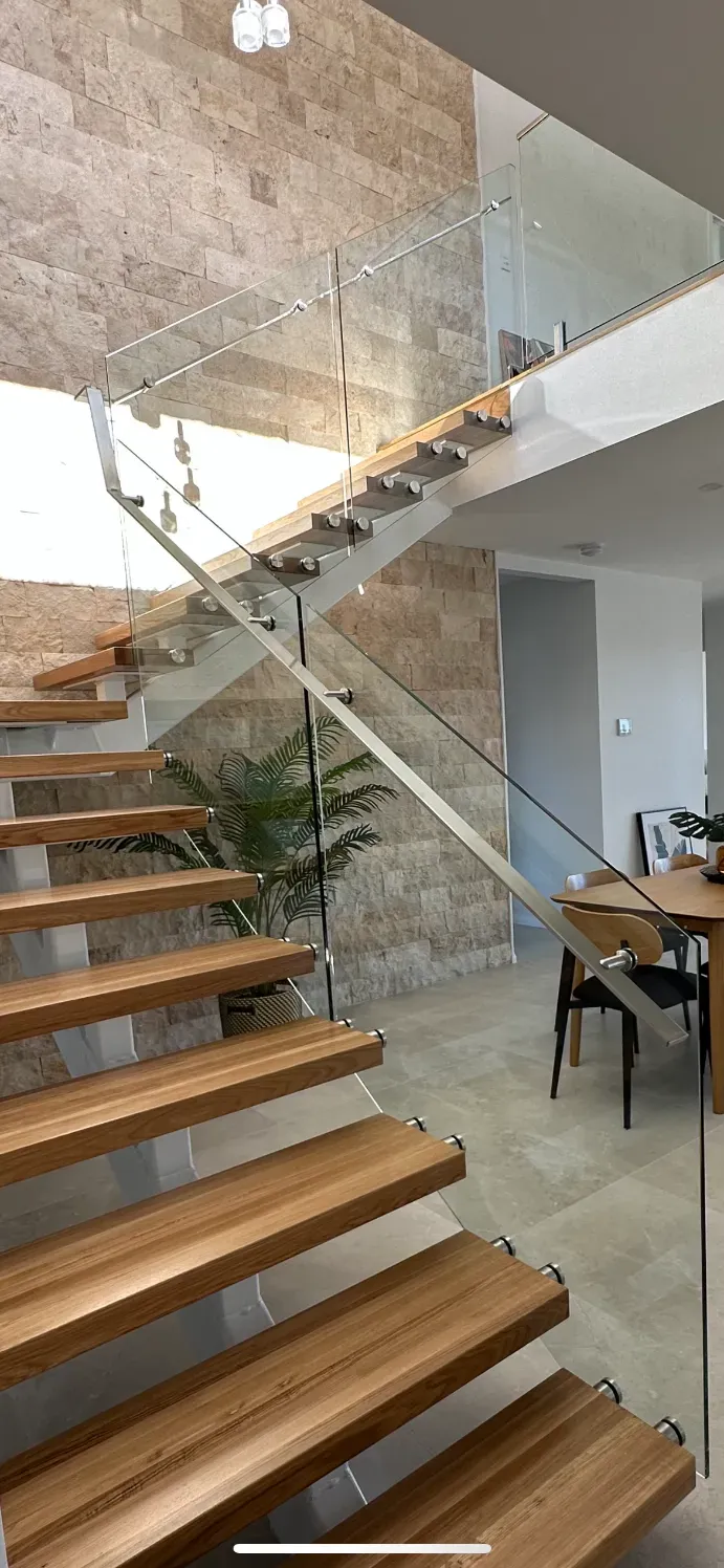 A Wooden Staircase With A Glass Railing In A HoUSE — Mid Coast Glass Fencing In South West Rocks, NSW
